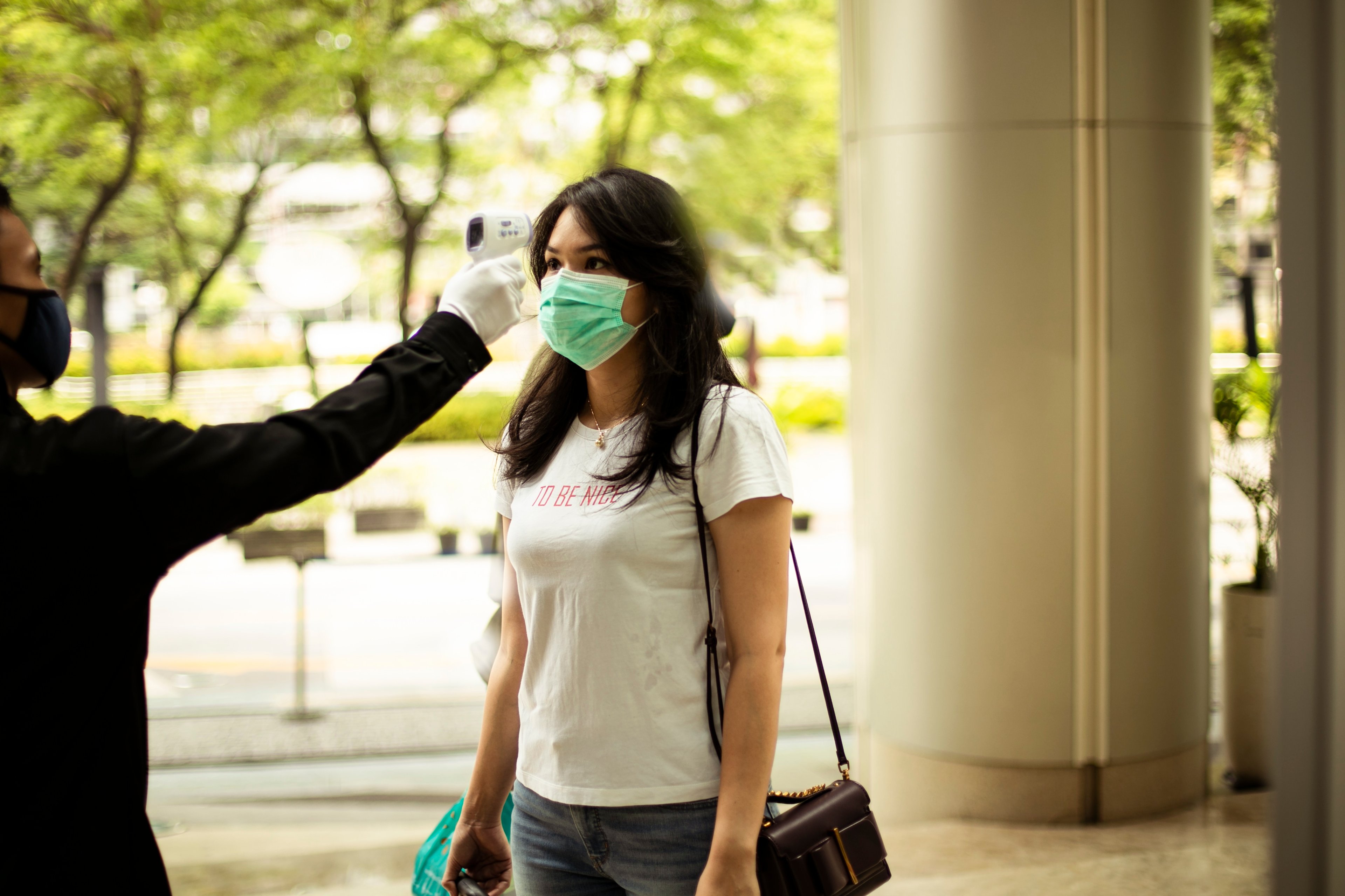 A woman outside a store getting her temp checked. 