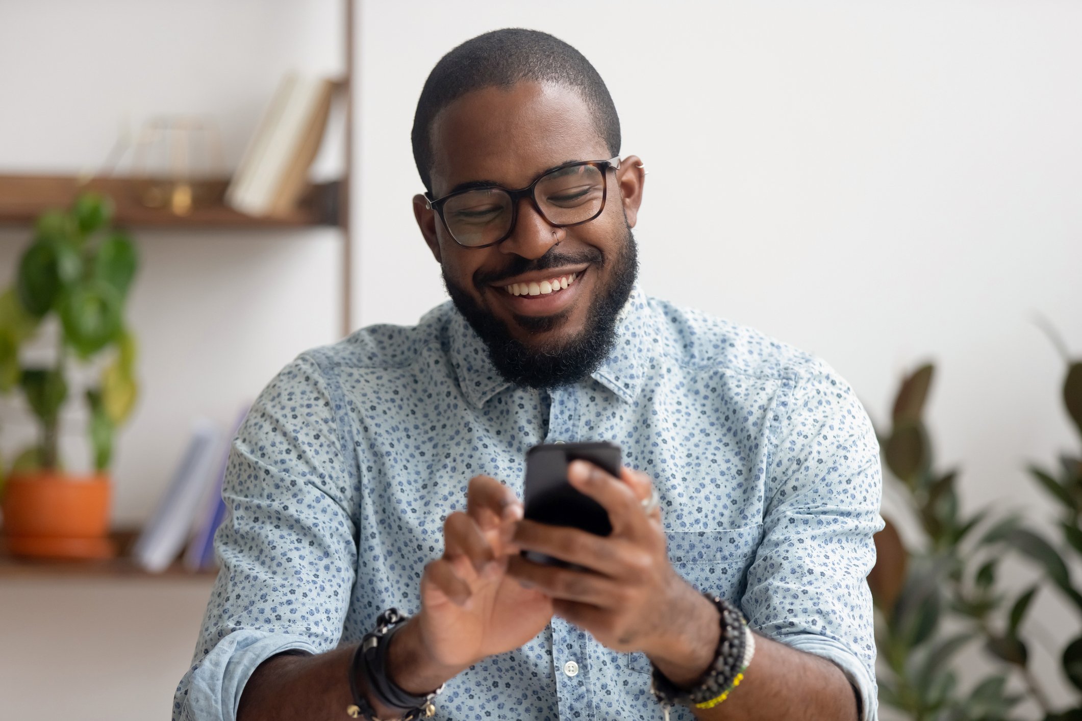 Man smiling while tapping on mobile phone