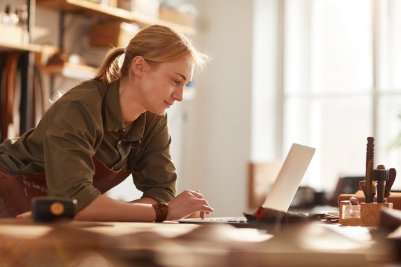 Woman in her workshop working on her laptop.