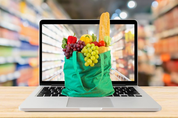 A bag of groceries on top of a laptop. 