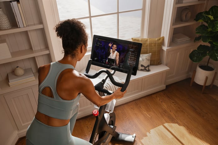 A woman riding a Peloton stationary bicycle at home. 