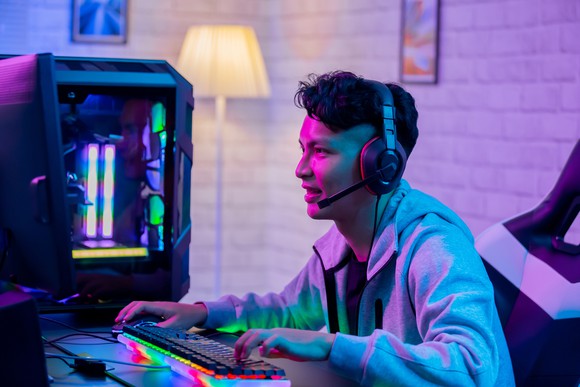 A young man playing a video game on a PC.