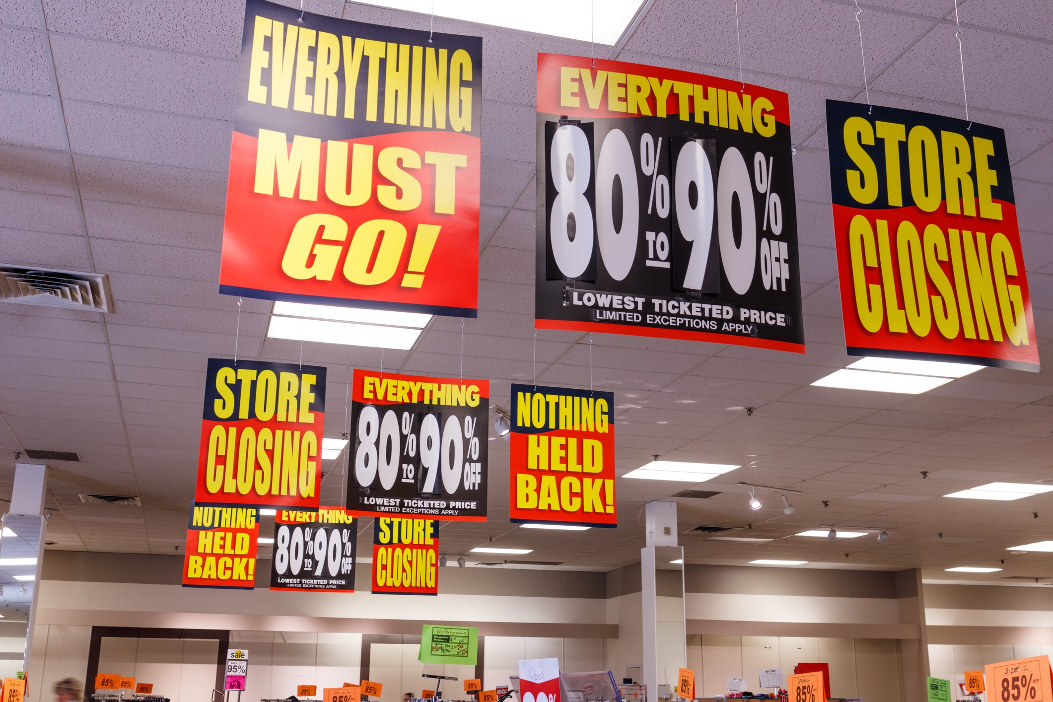 Store closing signs hanging from a ceiling of a store