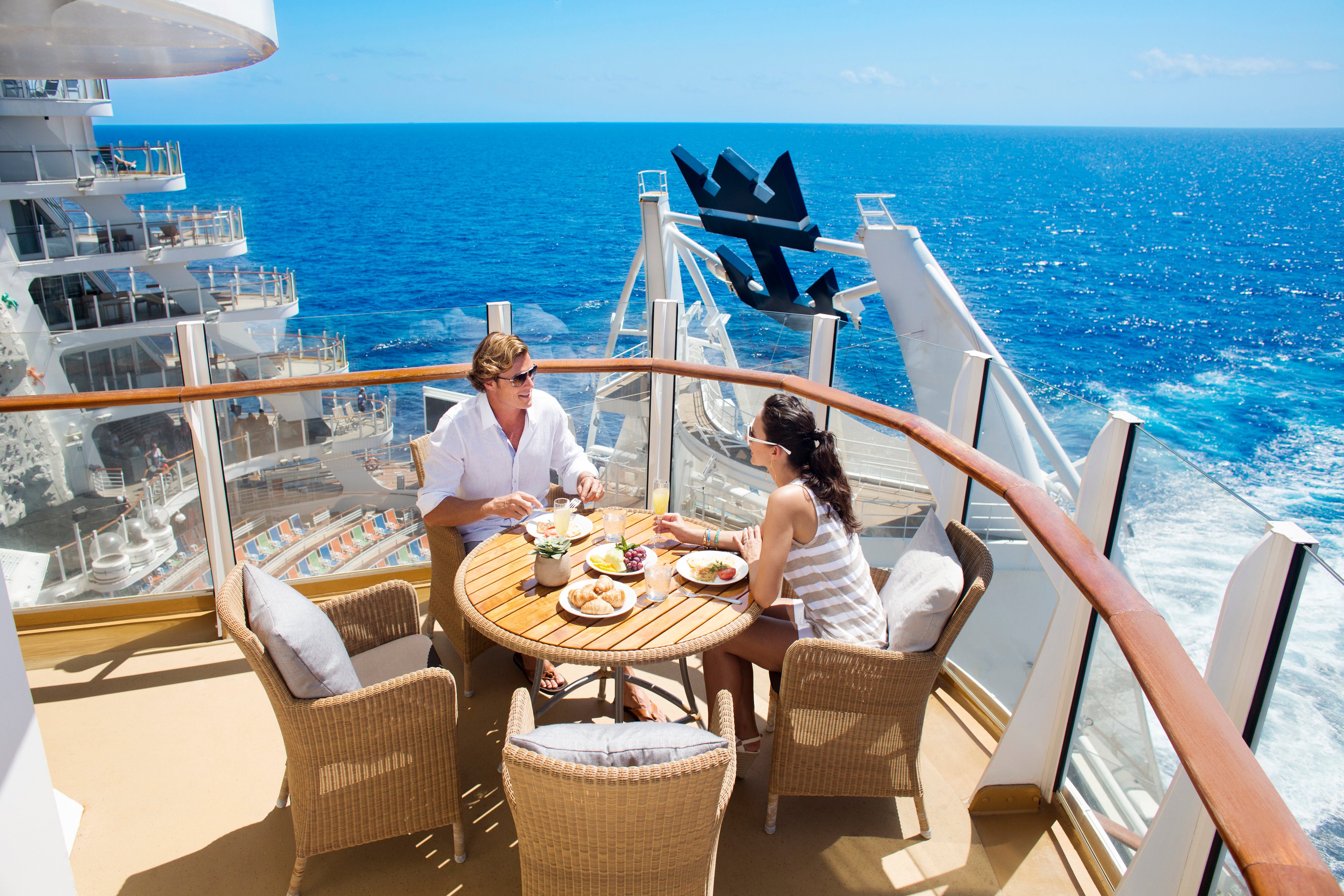 A couple enjoying a meal on an outdoor deck of a Royal Caribbean cruise ship.