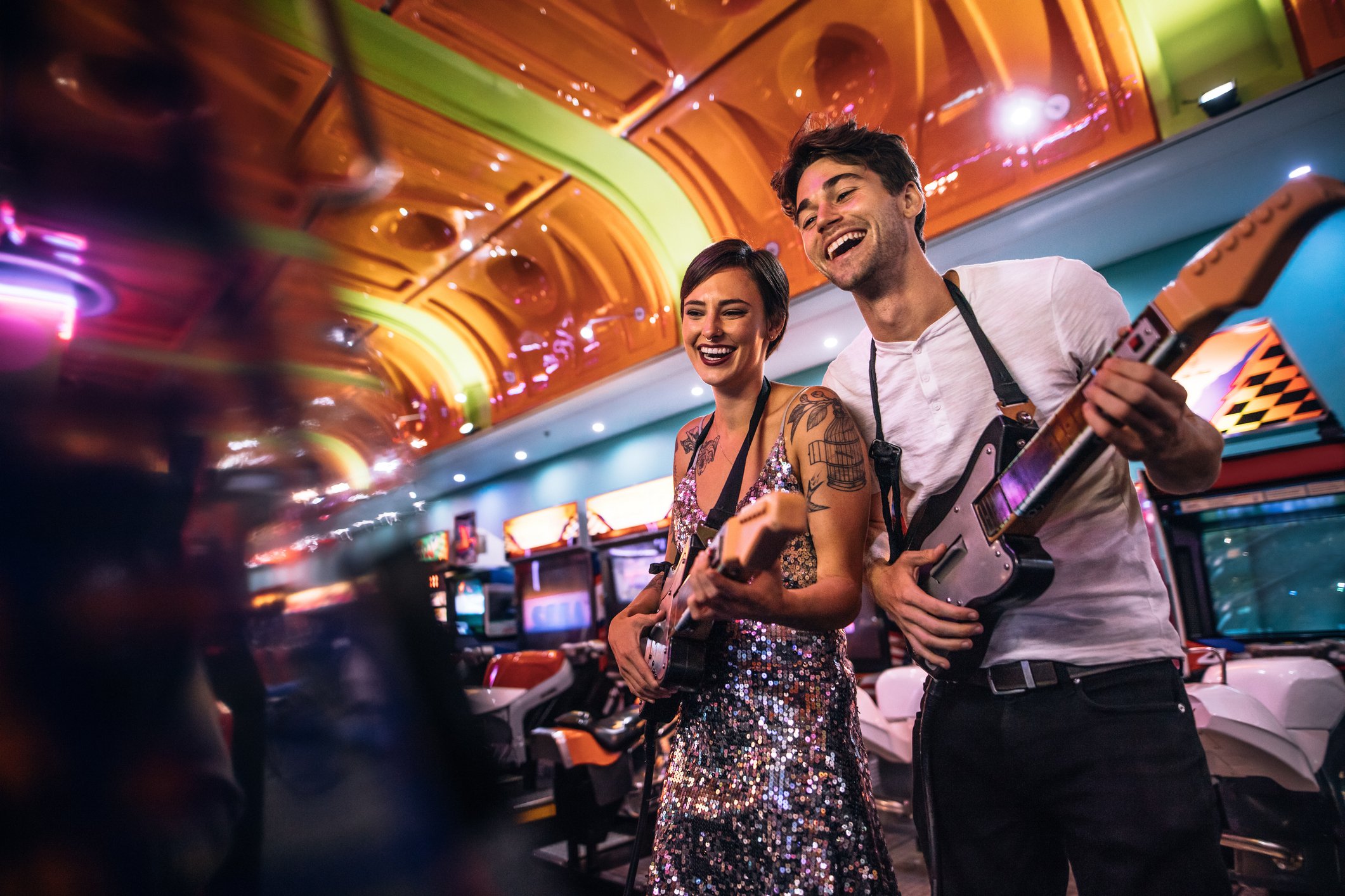 Man and woman playing a guitar game at an arcade.