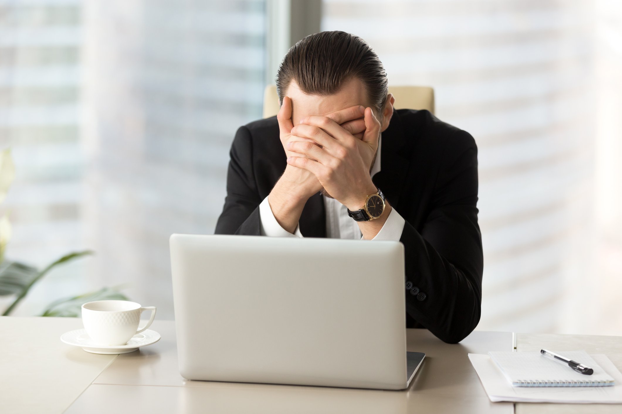 Man with hands over face in front of laptop