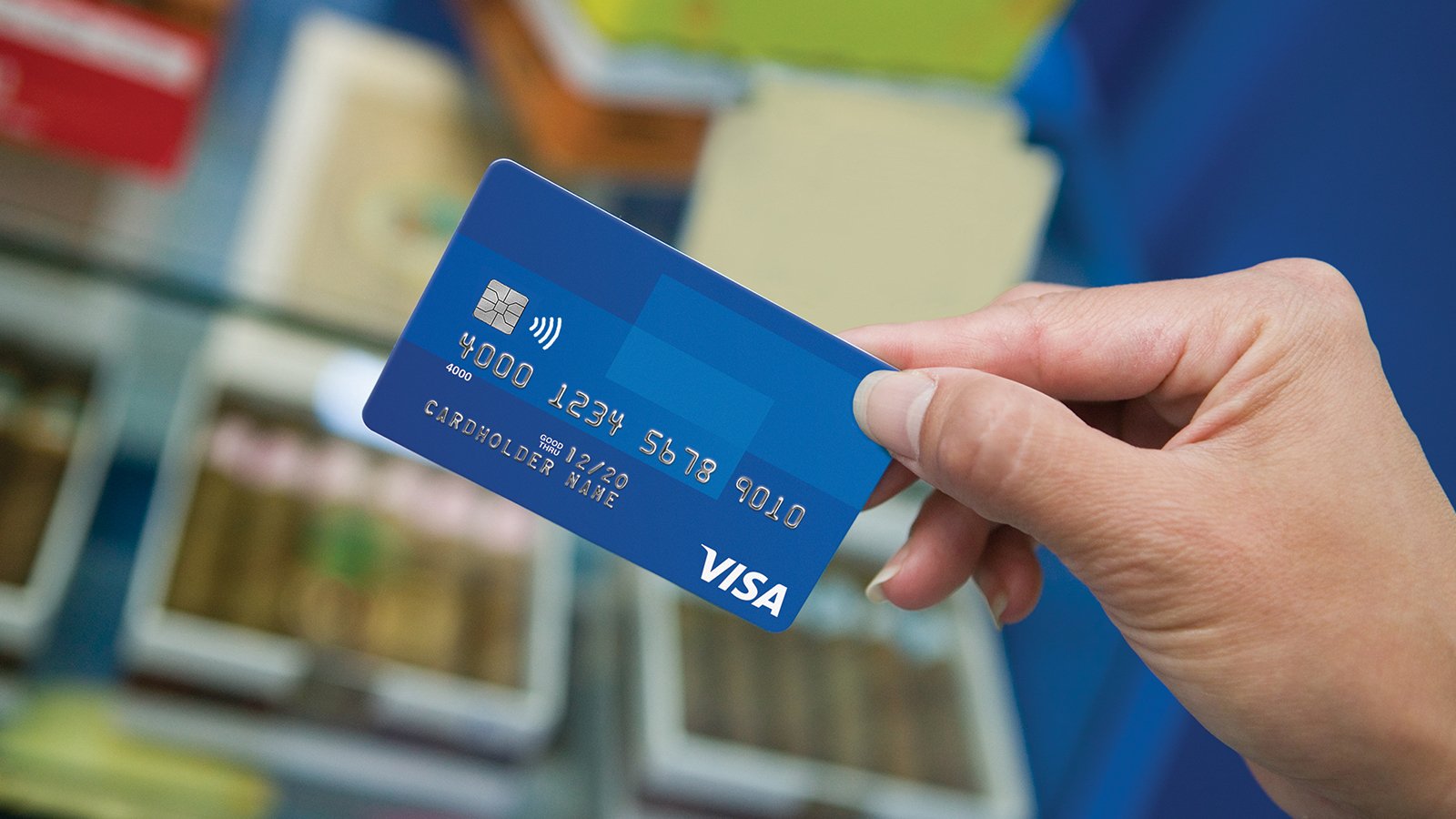 Hand holding a blue Visa card.