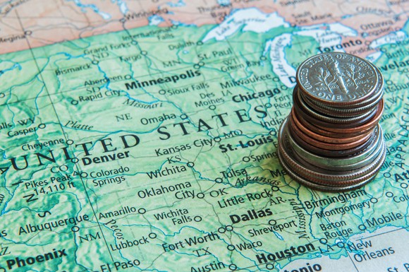 A partial map of the United States is shown with a stack of U.S. coins sitting on it.