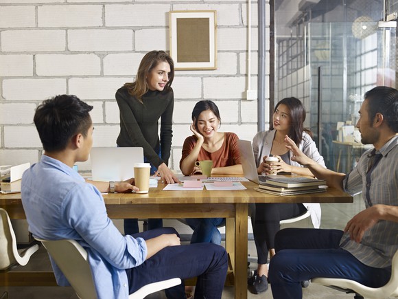 Three women and two men chatting at a table