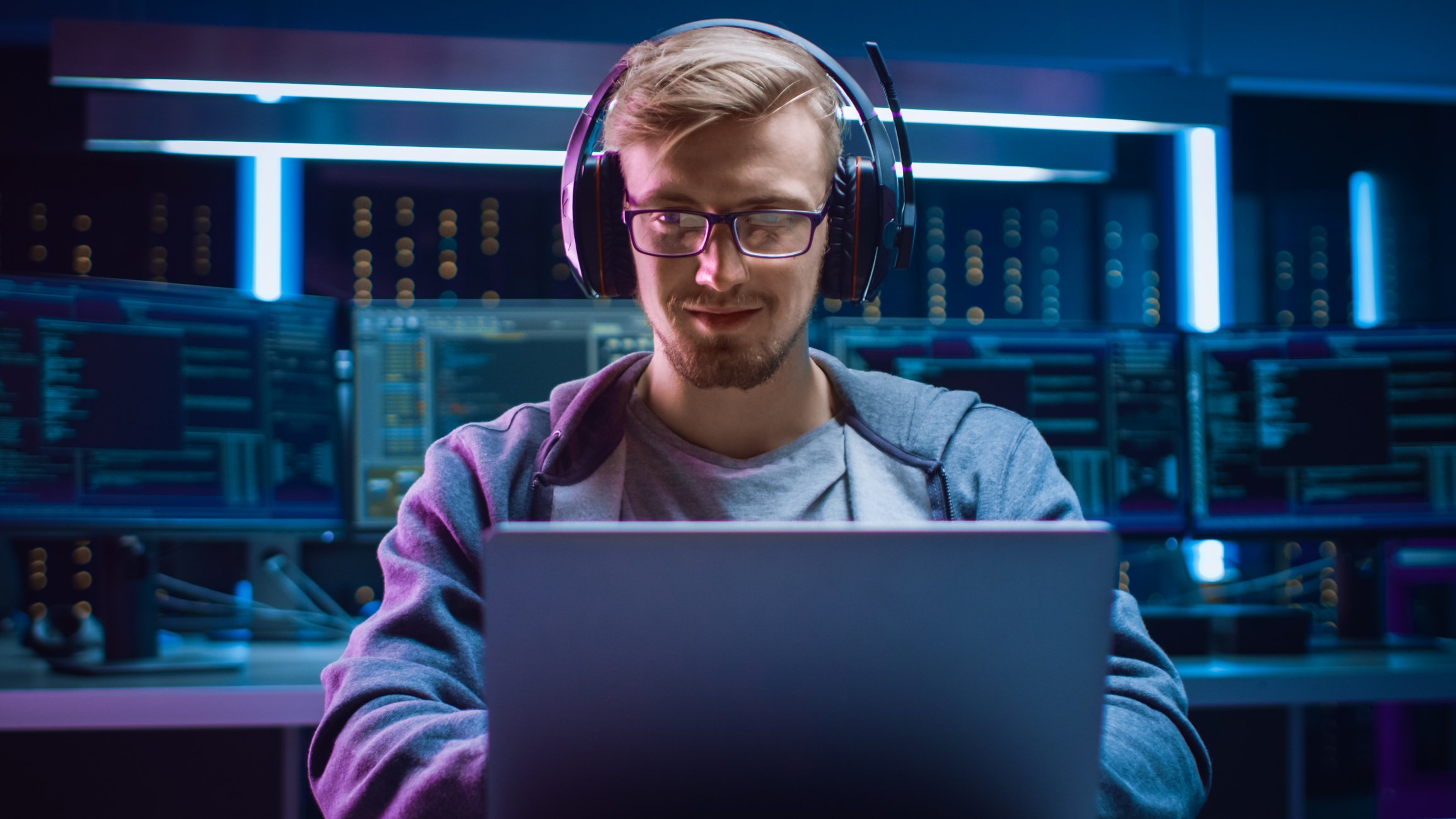 A young man uses a notebook computer while wearing headphones.