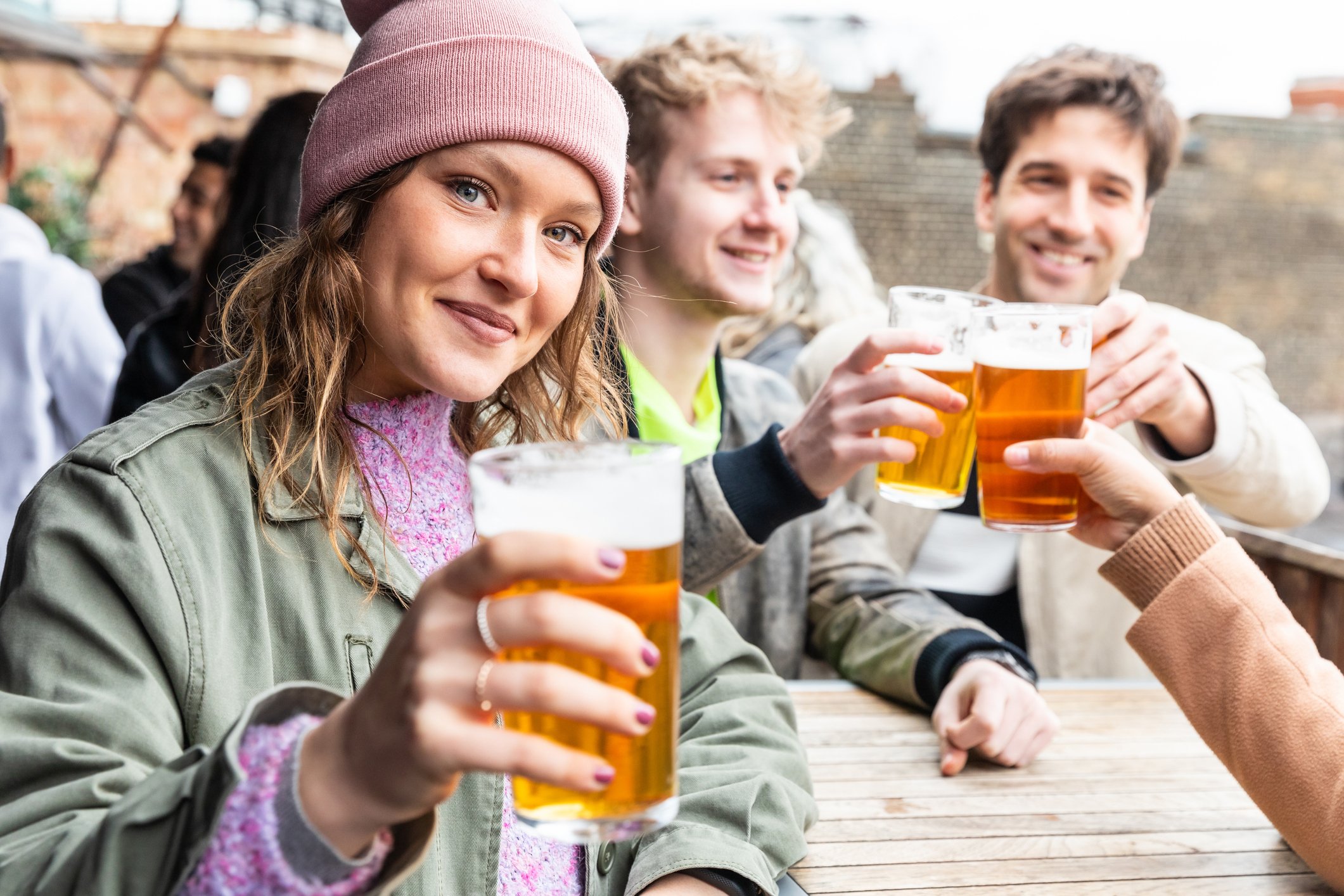 Friends holding tall glasses of beer. 