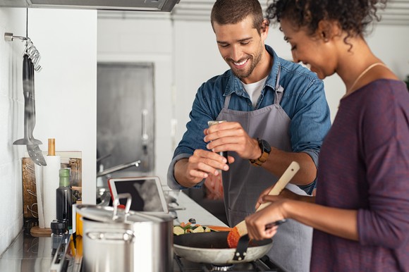 Two people cooking food on a stove