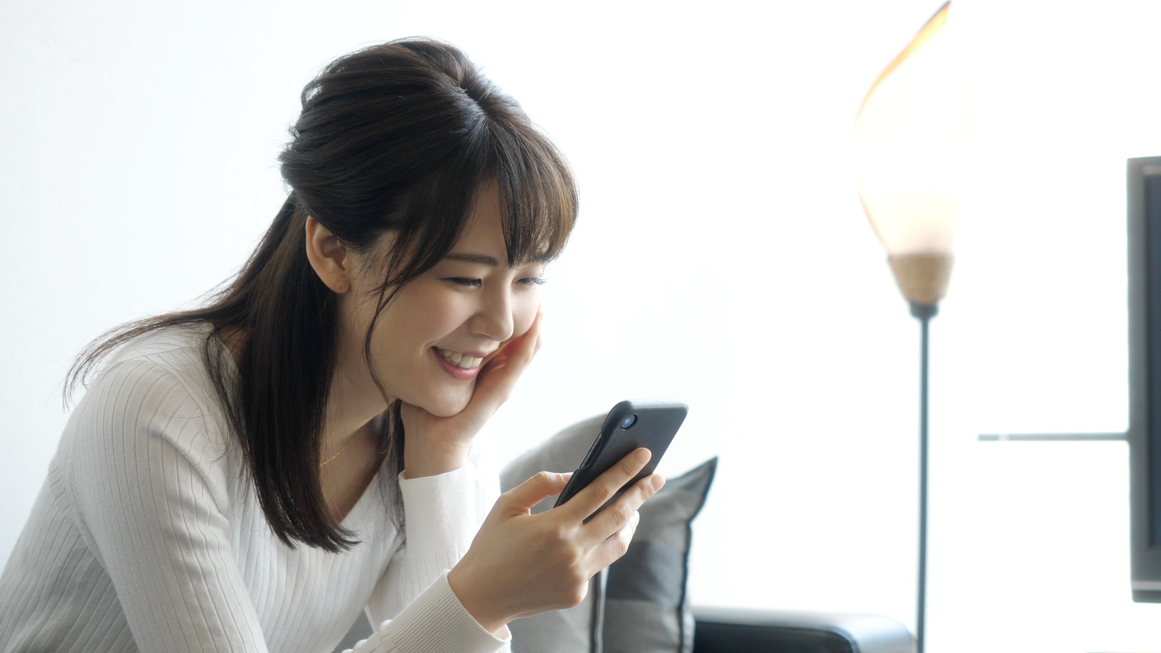 A young woman checks her smartphone at home.