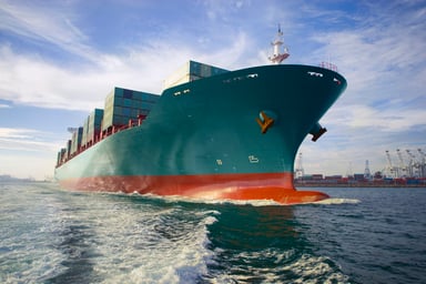 a loaded cargo ship sails out of port