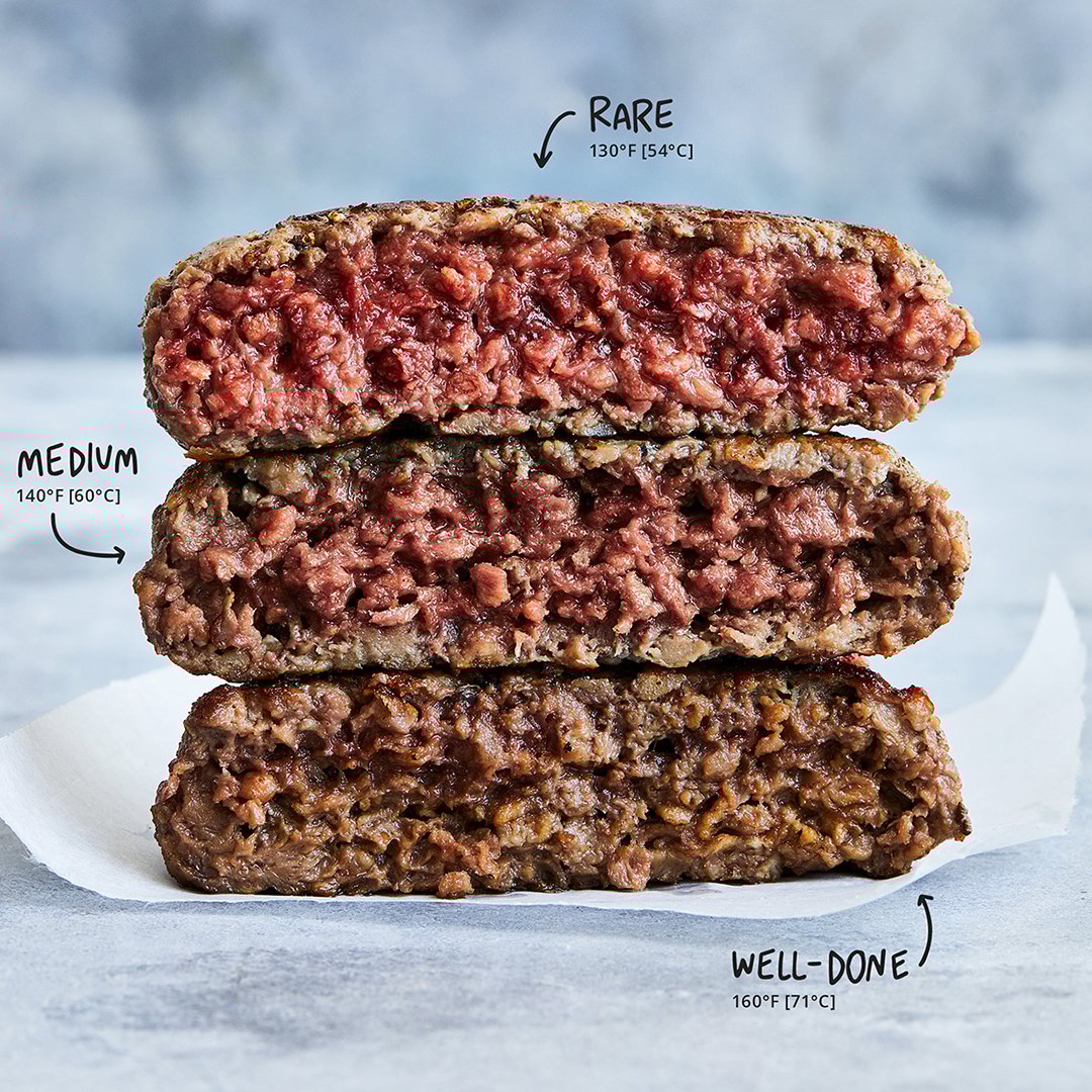 Three meat-substitute patties from Impossible Foods stacked on top of each other to show varied coloration.