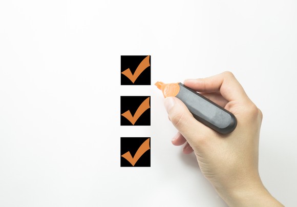 Hand holding marker with checks in three checkboxes