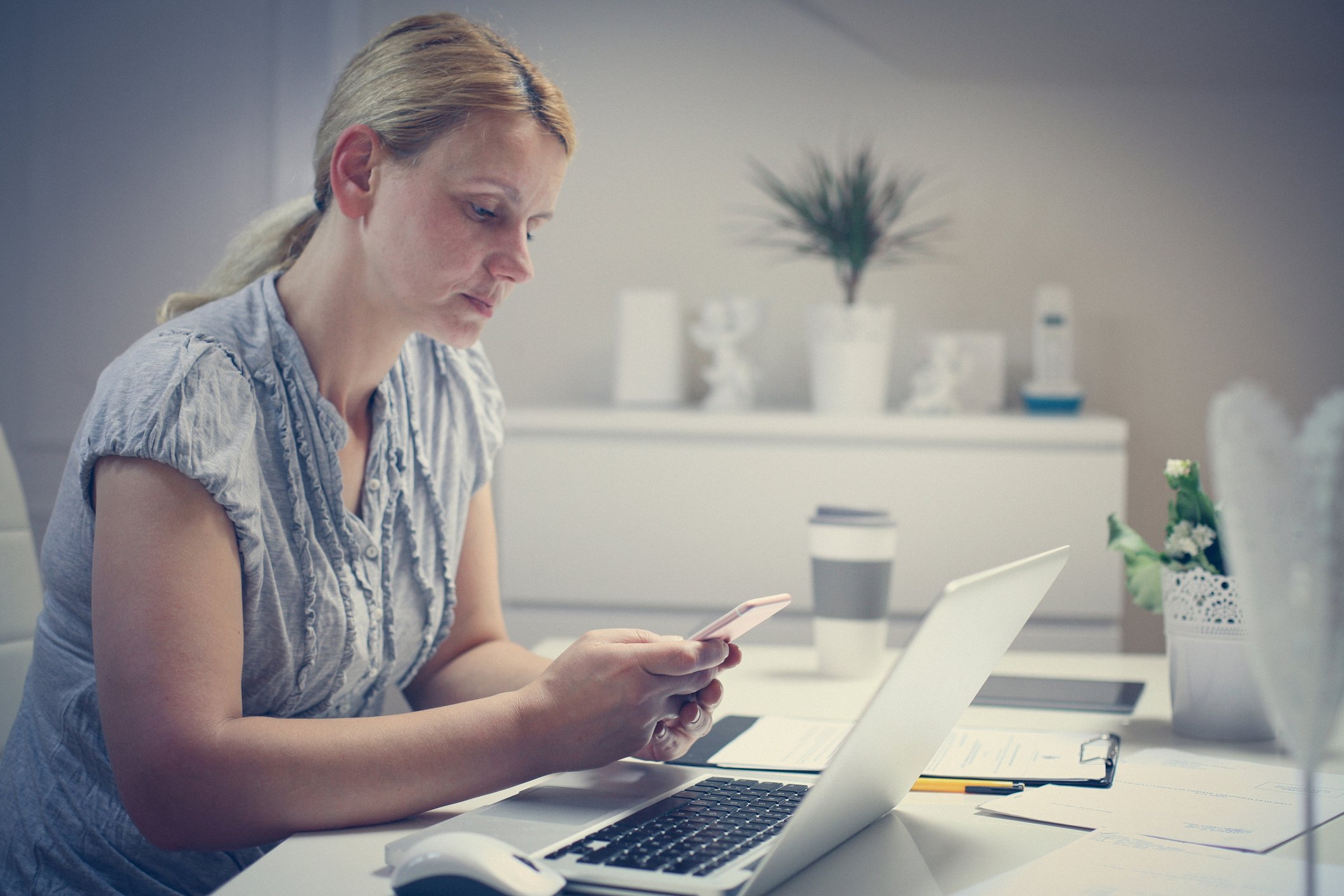 Worried woman looking at her phone in home office.