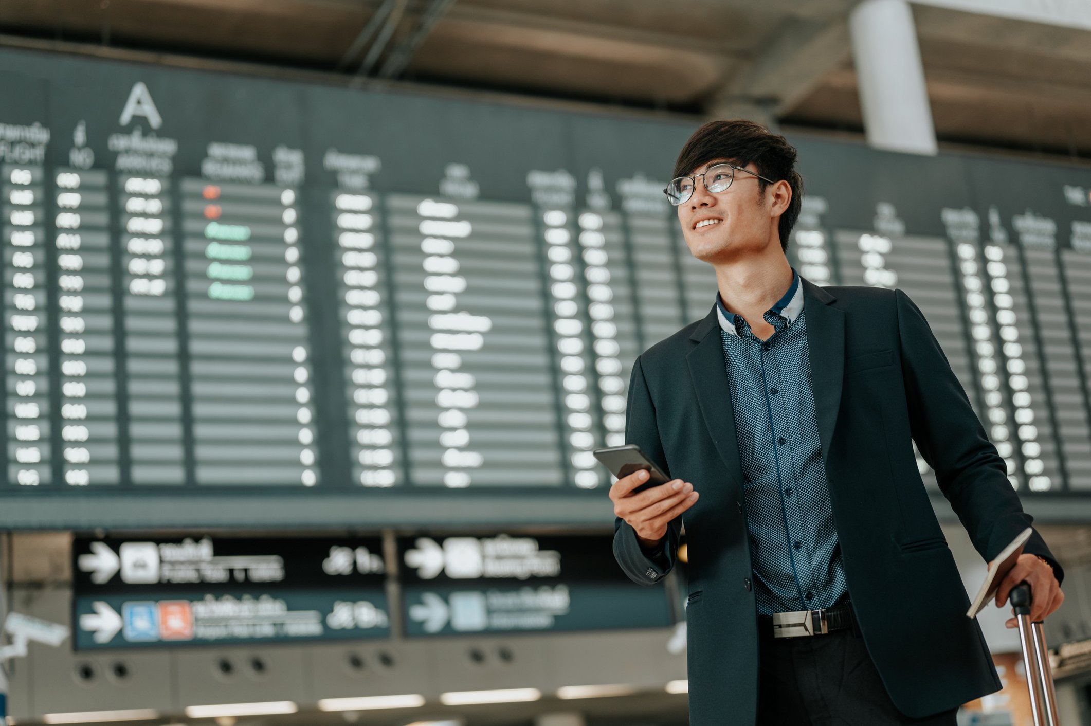 A man with a smartphone in an airport.