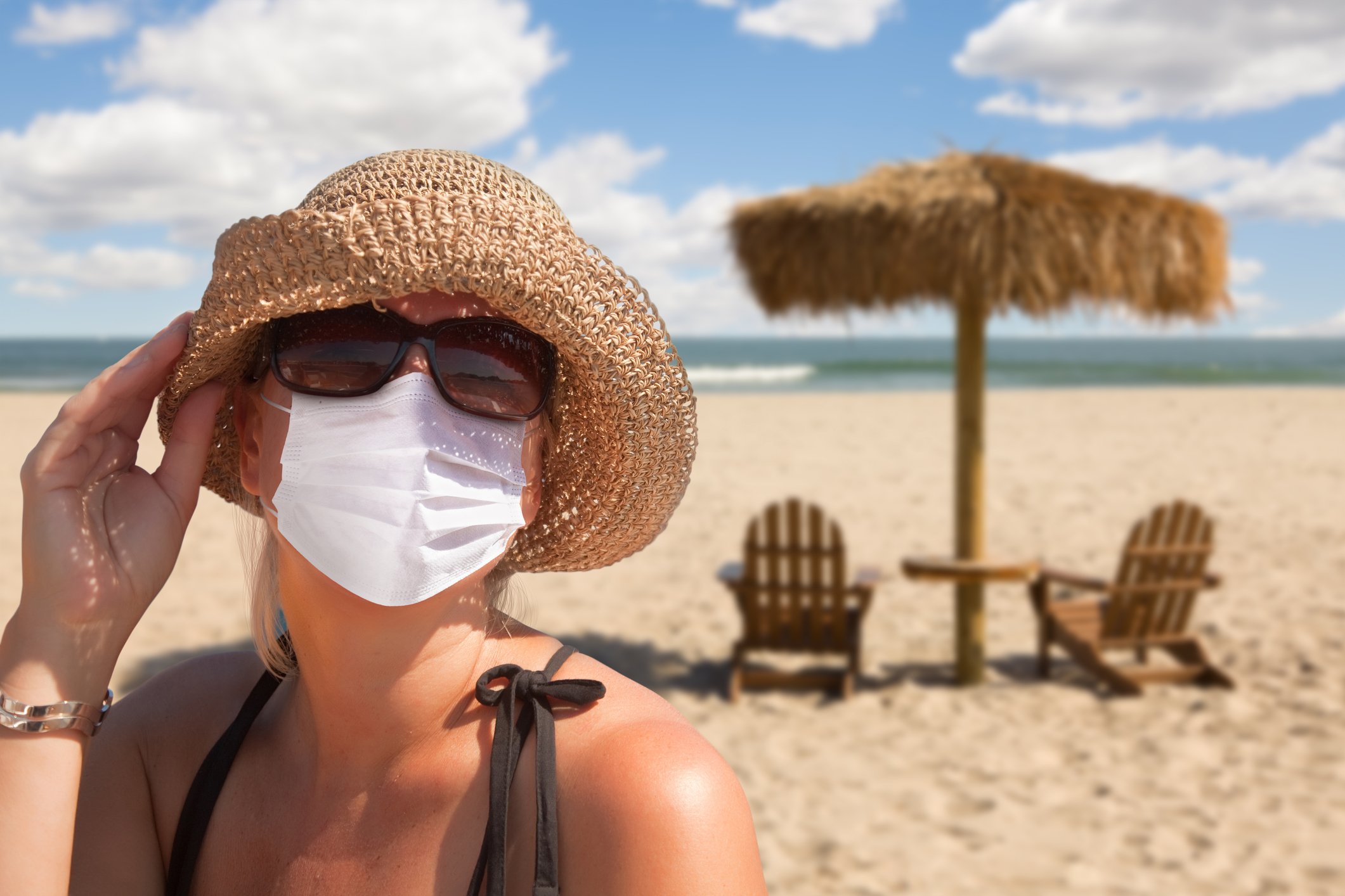 Woman on a beach wearing disposable face mask. 