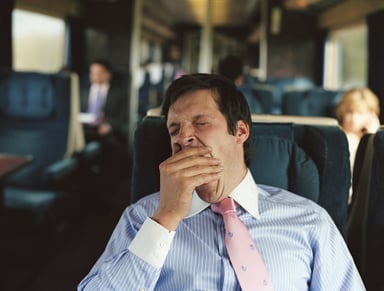 a businessman yawns on a train