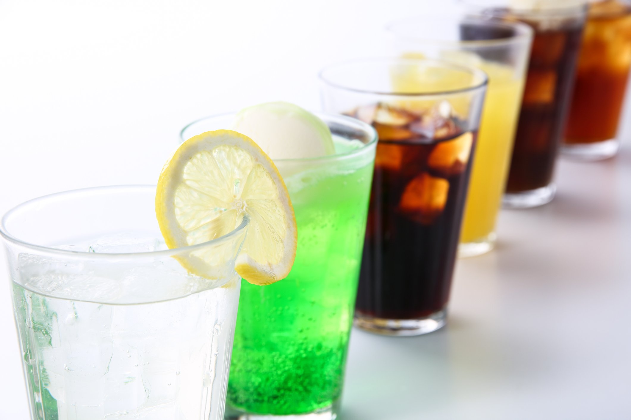 Assorted soft drinks arranged in a row of transparent cups.