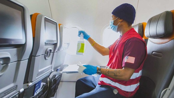 A JetBlue employee cleans an airplane interior.