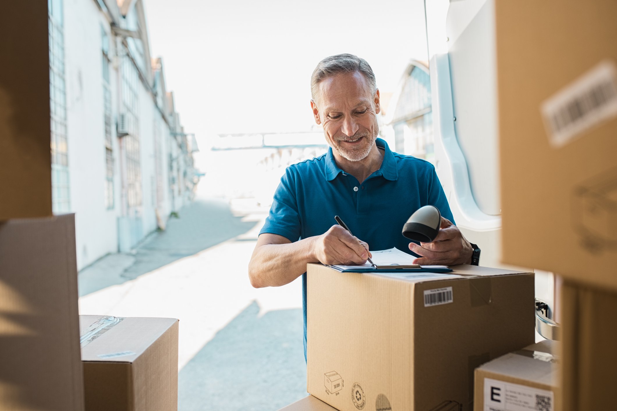 Man with package deliveries at back of truck.