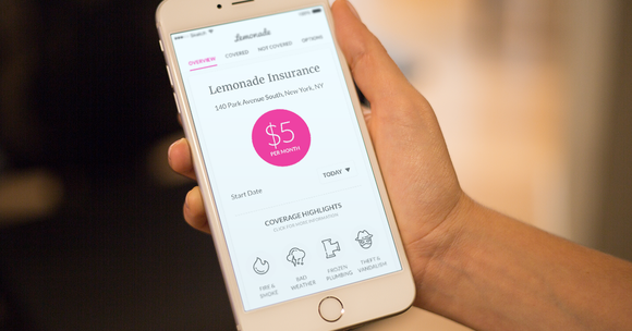 Hand holding smartphone with Lemonade insurance app shown.
