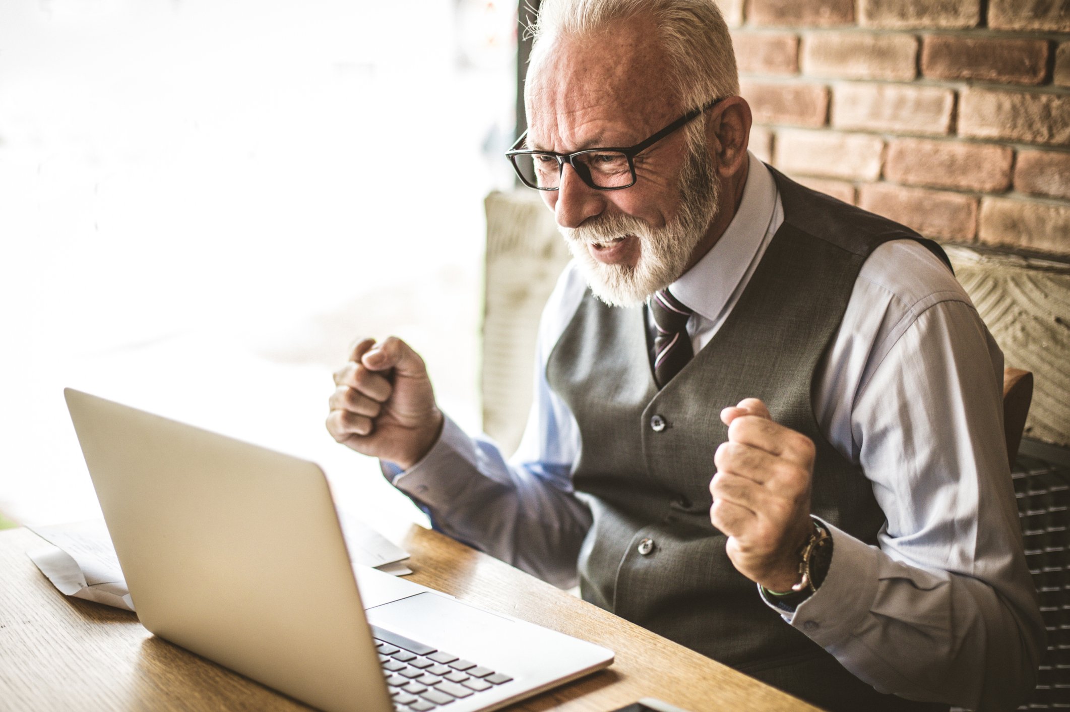 Older man looking at laptop with happy expression.