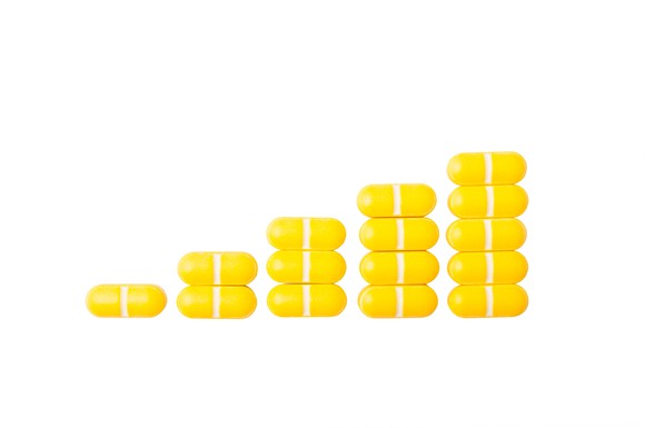 Stacks of yellow pills in the form of a rising bar graph.