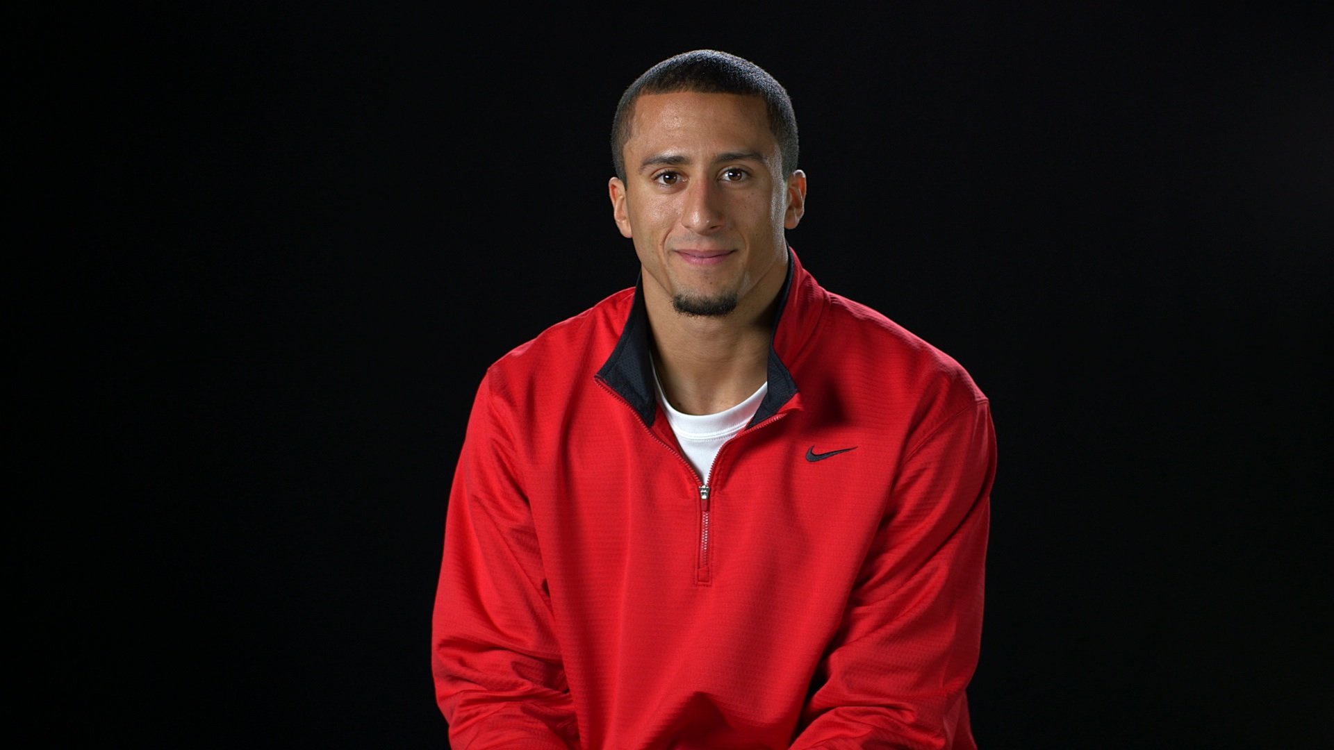 Colin Kaepernick smiling wearing a Nike jacket.