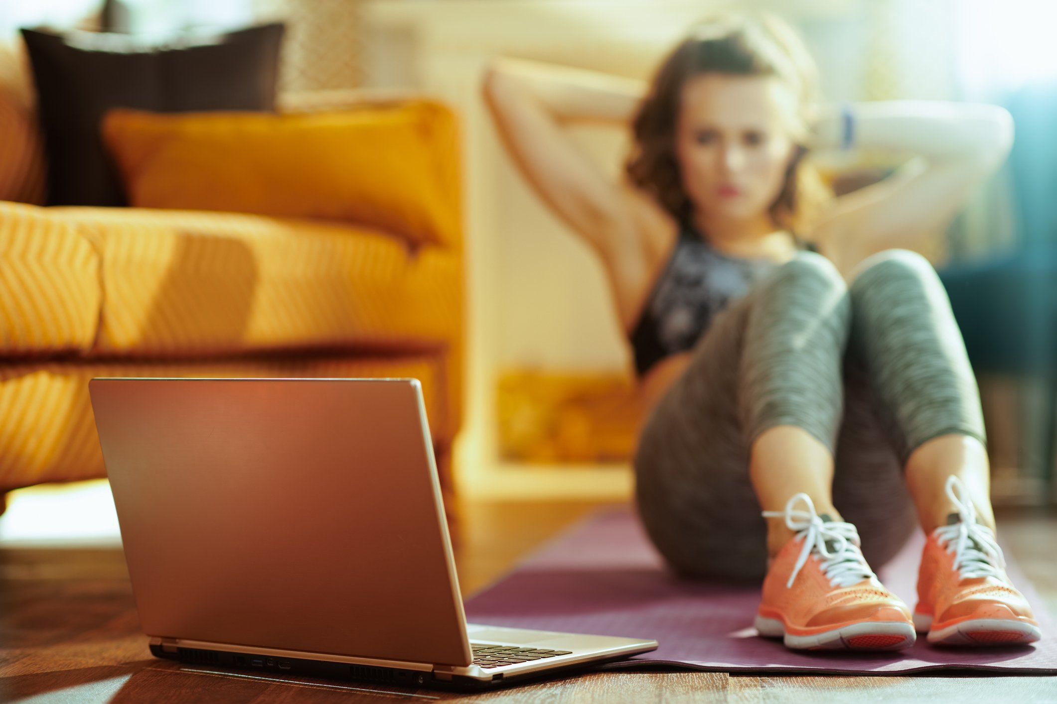 Woman doing abdominal crunches while watching laptop.