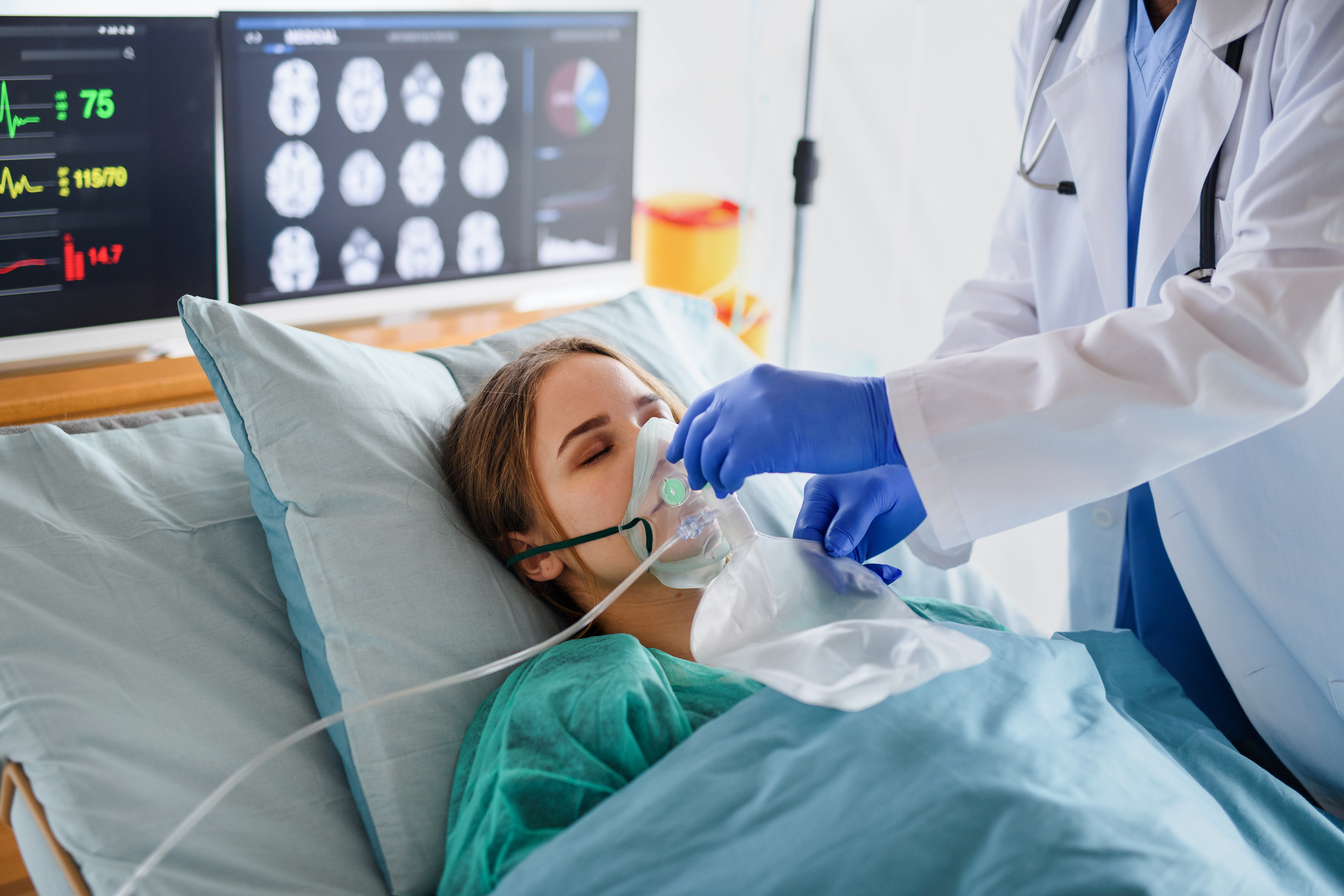 A doctor positions a breathing mask over a patient's face.