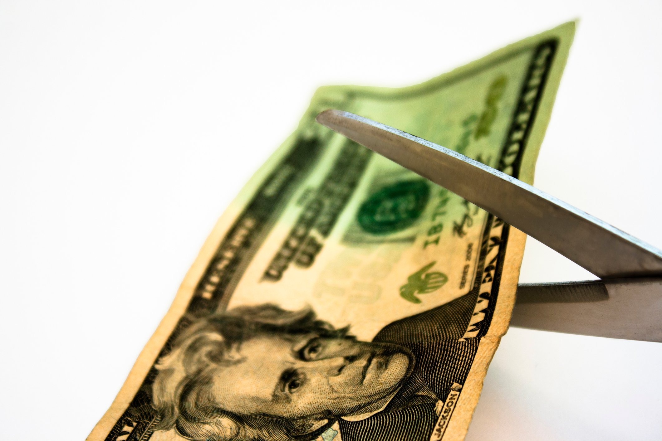 A $20 bill about to be cut by scissors.