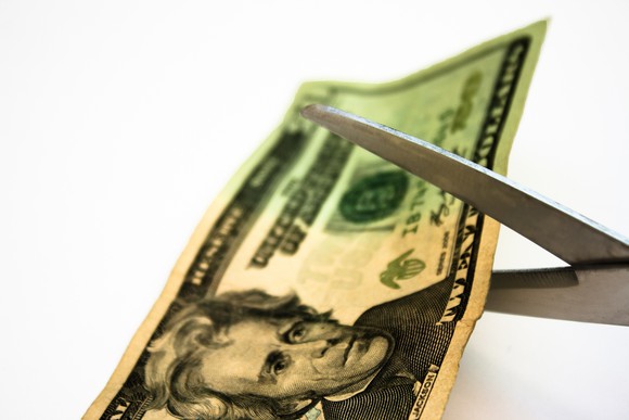 A $20 bill about to be cut by scissors.