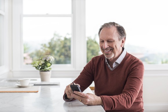 A man smiling while checking his blood sugar on a connected device. 