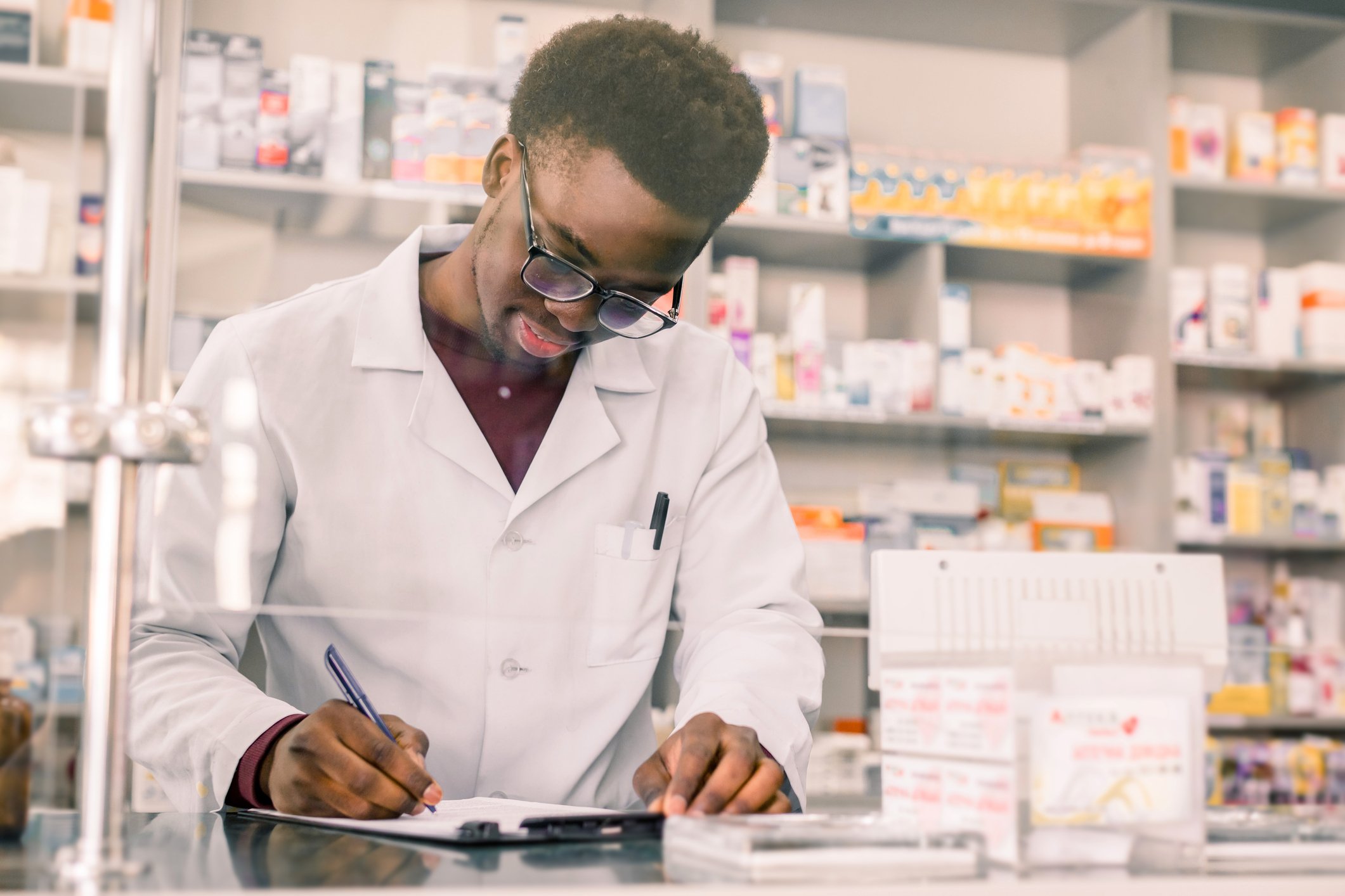 A pharmacist filling out a form behind the counter