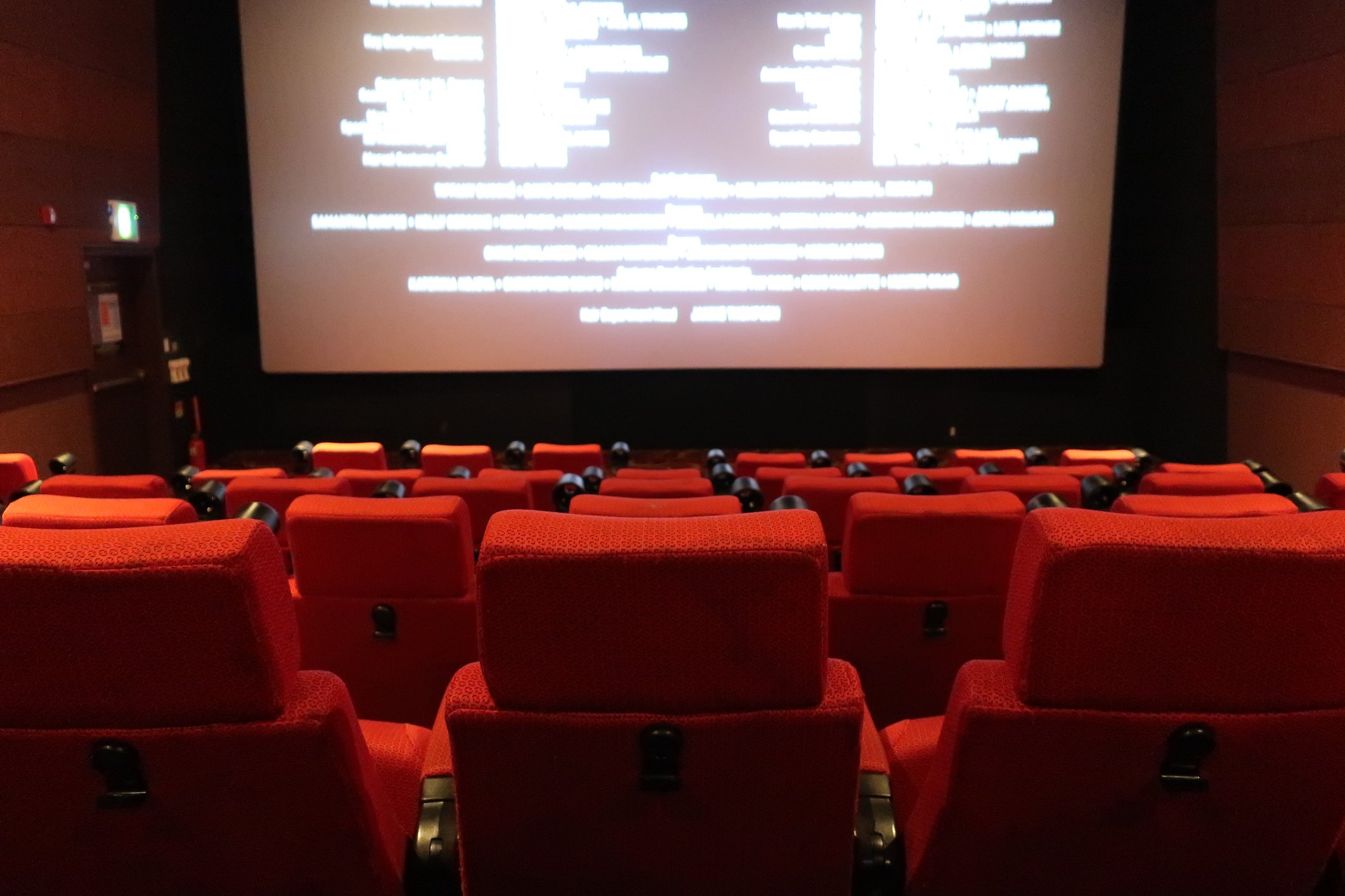 An empty movie theater with the credits rolling on the screen.