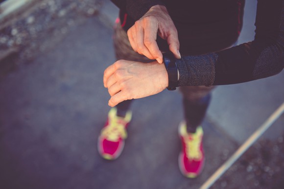 A woman checks her wristband fitness tracker.