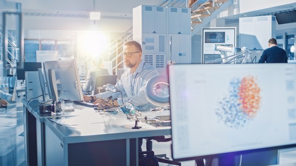 A man designs a chip on a computer in an advanced lab. 