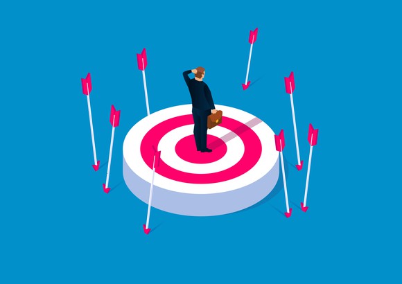 Businessman standing in the center of a target surrounded by arrows that missed their mark. 
