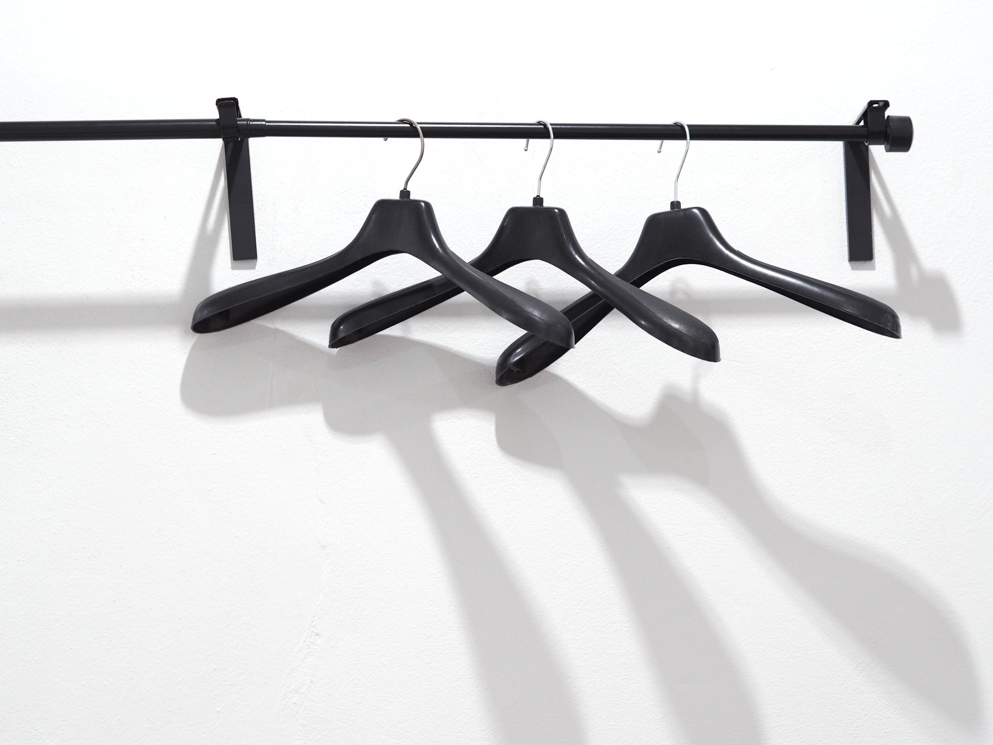 Three empty hangers on a clothing rack. 