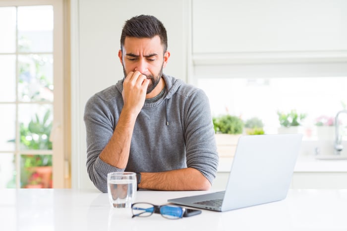 Man at laptop biting nails