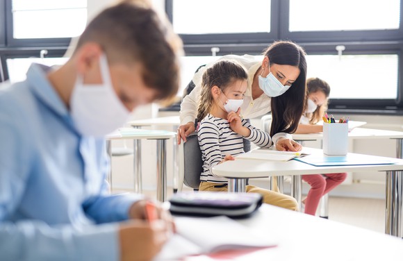 A teacher and children wearing face masks in the classroom