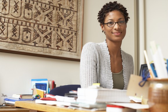 A smiling woman sits at an office desk.