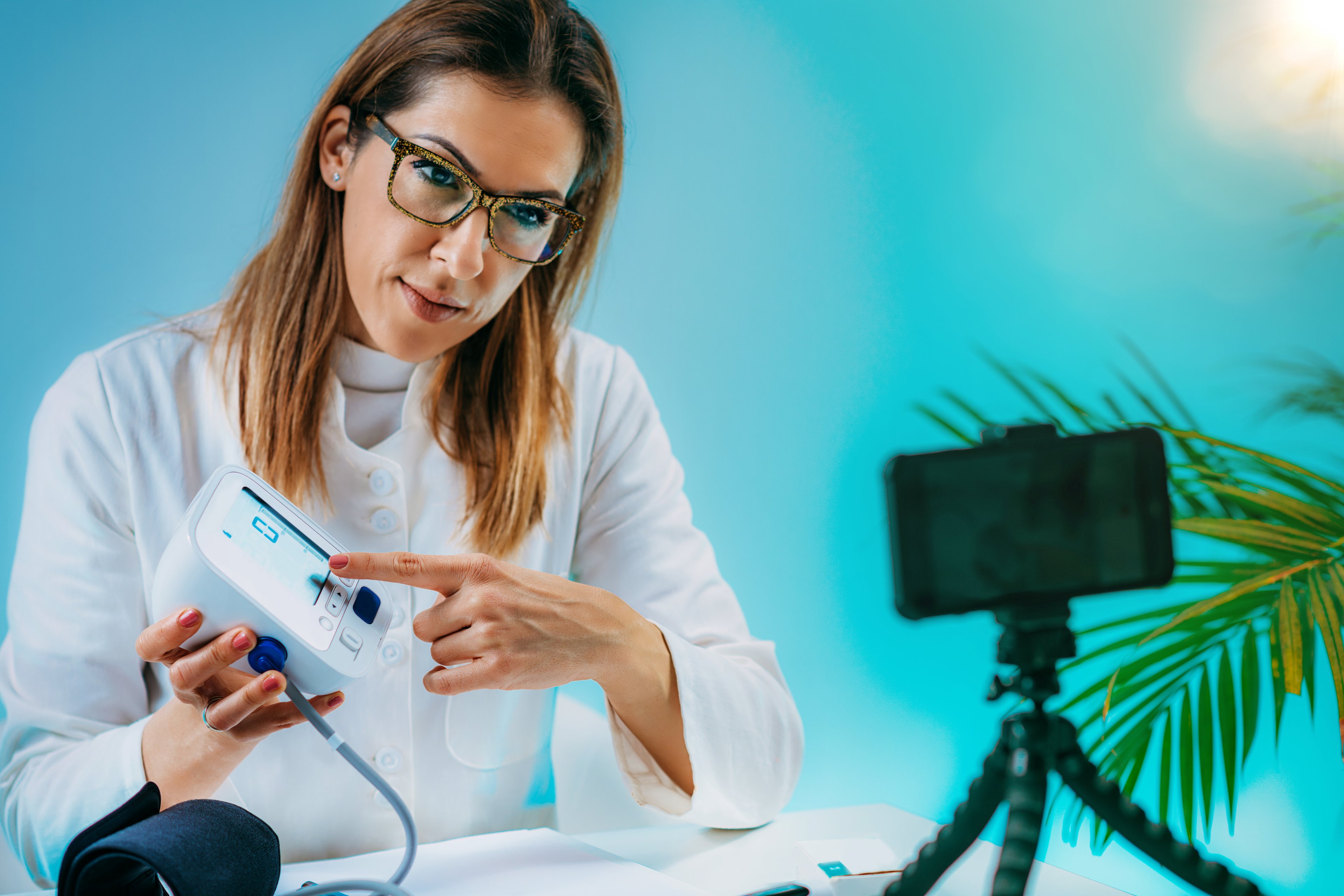 Medical doctor recording video instructions for patient and demonstrating how to measure blood sugar.