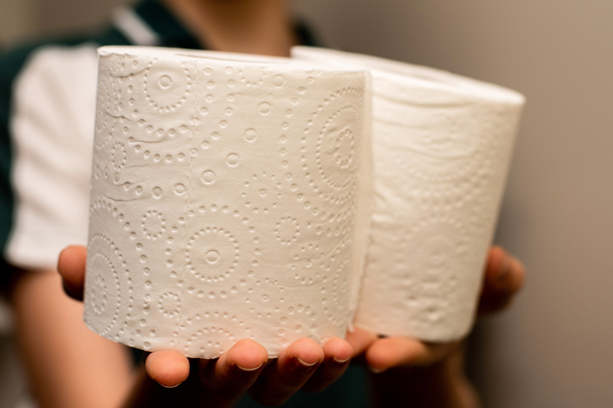 A woman holds out two rolls out toilet paper.