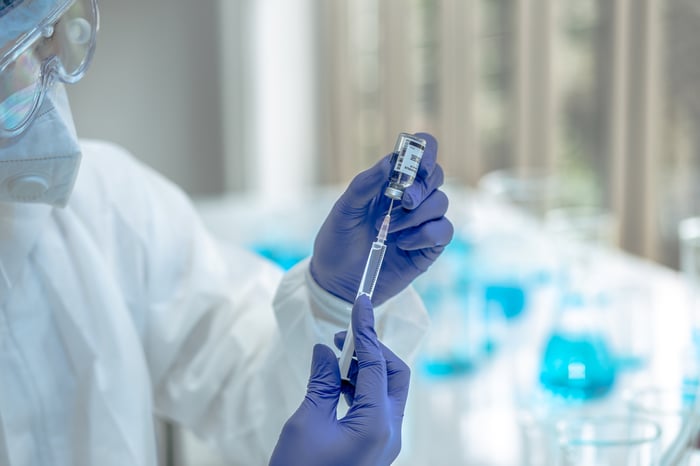 Scientist with syringe and vaccine bottle