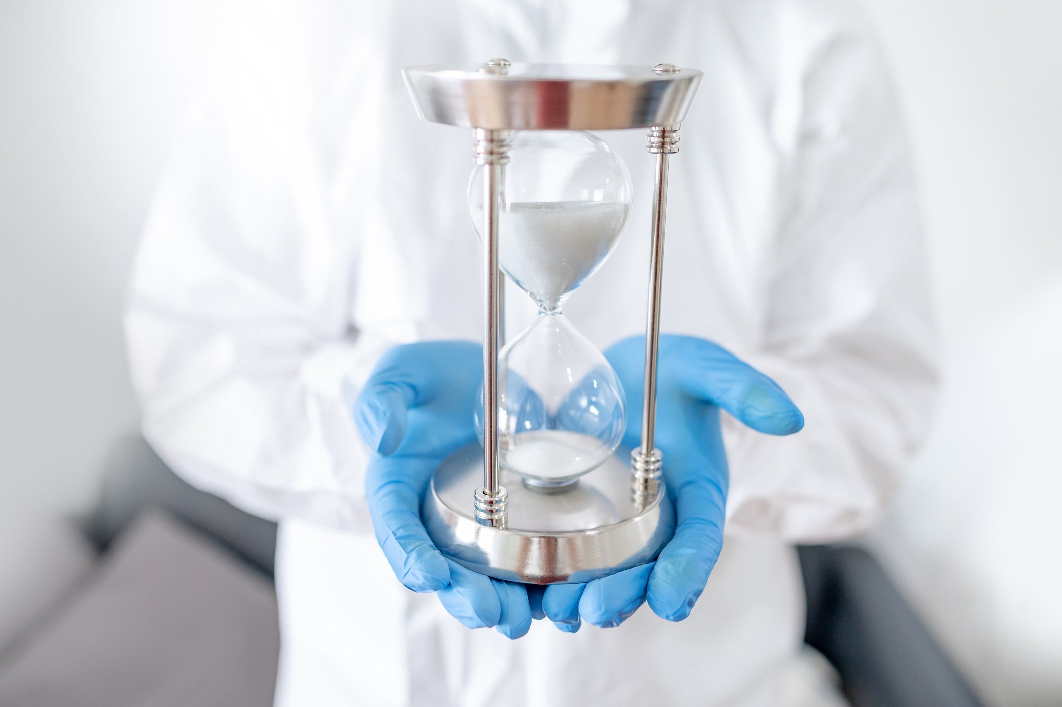 Scientist holding an hourglass with gloved hands
