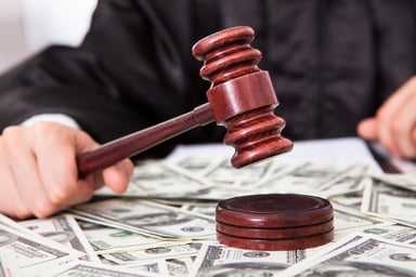 Judge holding gavel and $100 bills
